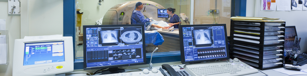 MRI images on computer screens with MRI machine in background