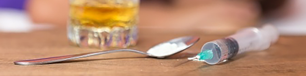 whiskey glass, spoon with white powder, and injection needle